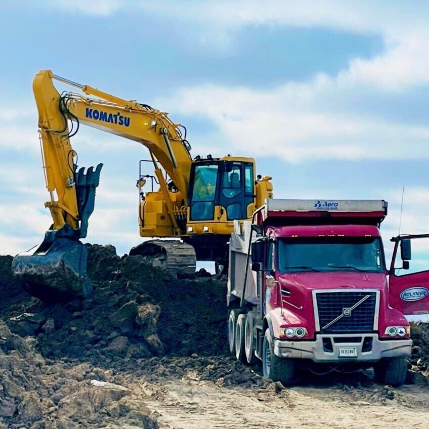 A dump truck and a tractor on top of some dirt.